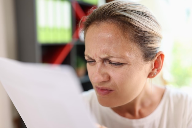 Foto porträt einer konzentrierten frau, die versucht, papiere zu lesen, die die augen zusammenkneifen, um das weibliche haben klarer zu sehen