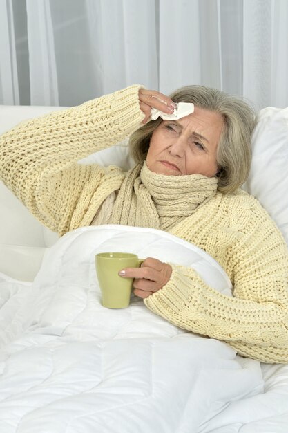 Porträt einer kranken Seniorin, die auf einer weißen Couch liegt