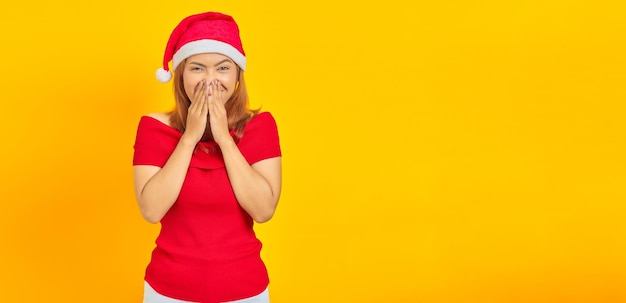 Porträt einer lachenden jungen Asiatin mit Weihnachtsmütze, die den Mund mit der Hand bedeckt