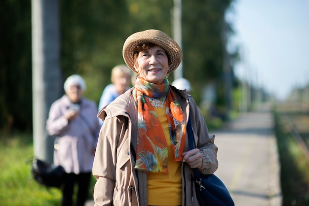 Porträt einer lächelnden älteren Frau mit Sommerhut, die während der Covid-19-Pandemie unterwegs ist