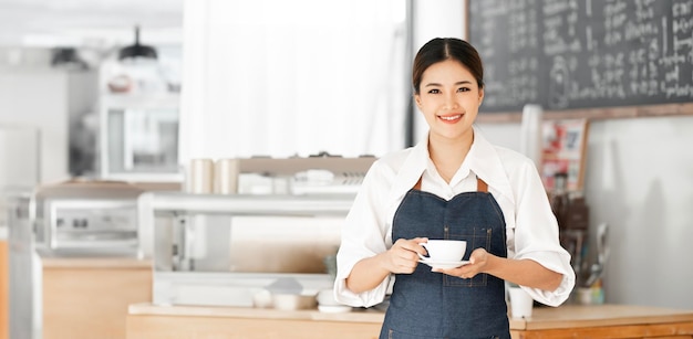 Porträt einer lächelnden asiatischen Frau, Barista, Kaffeehausbesitzerin, die eine Tasse Kaffee hält, KMU-Unternehmer, Verkäufer, Geschäftskonzept