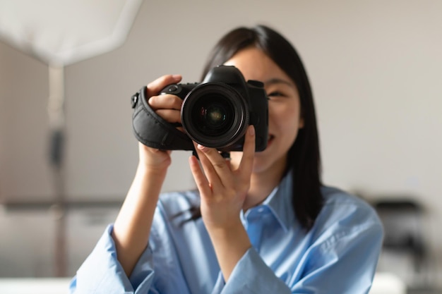 Porträt einer lächelnden asiatischen Frau, die eine Kamera beim Fotografieren hält