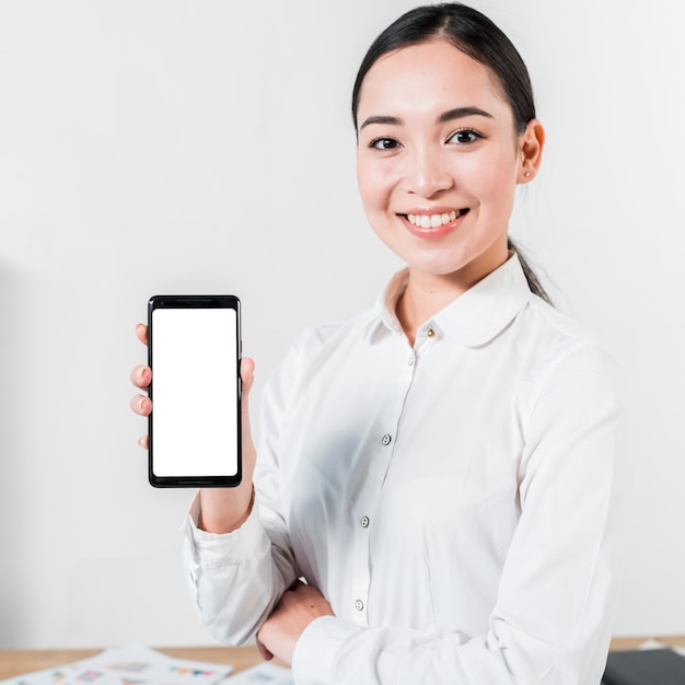 Foto porträt einer lächelnden asiatischen jungen geschäftsfrau, die handy des leeren bildschirms zeigt