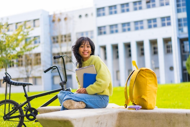 Porträt einer lächelnden asiatischen Studentin, die mit einem Fahrrad auf dem College-Campus sitzt