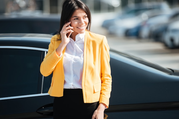 Porträt einer lächelnden attraktiven Geschäftsfrau, die am Telefon spricht