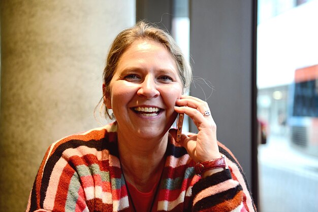 Porträt einer lächelnden Frau, die am Handy spricht