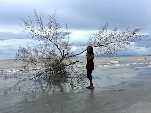 Porträt einer lächelnden Frau, die am Strand gegen den Himmel steht