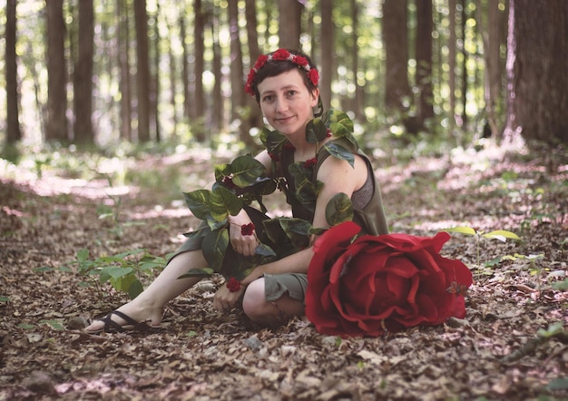 Foto porträt einer lächelnden frau, die auf dem land im wald sitzt