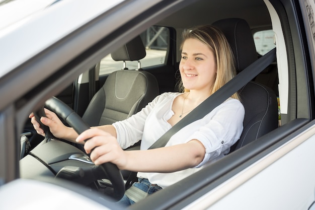 Porträt einer lächelnden Frau, die Auto fährt und in die Kamera schaut