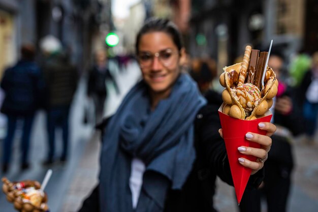 Foto porträt einer lächelnden frau, die ein dessert in der stadt hält