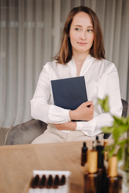 Porträt einer lächelnden Frau, die in einem Sessel sitzt. Ein Aromatherapeut in einer weißen Bluse sitzt im Büro