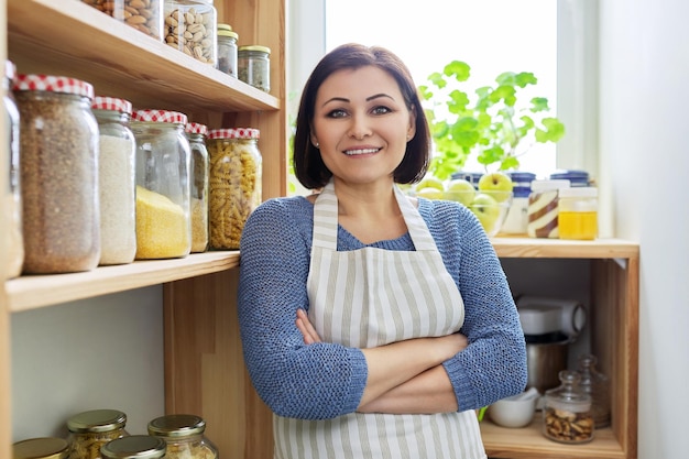 Porträt einer lächelnden Frau in einer Schürze in der Küche in der Speisekammer