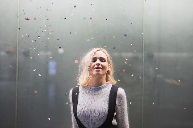 Foto porträt einer lächelnden frau mit blonden haaren, die an der wand steht