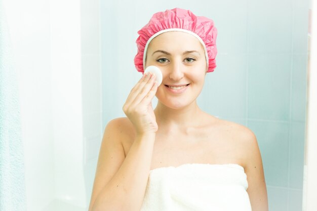 Porträt einer lächelnden Frau mit Gesichtscreme nach dem Duschen