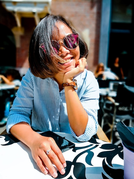 Foto porträt einer lächelnden frau mit sonnenbrille, die in einem café sitzt