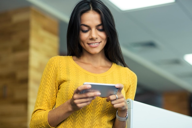 Porträt einer lächelnden Geschäftsfrau mit Smartphone im Büro