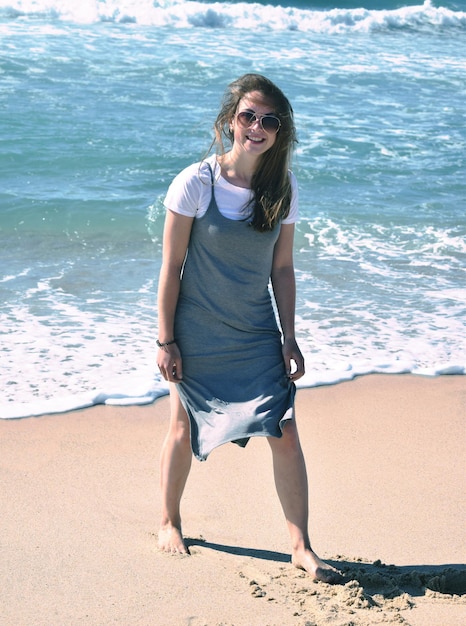 Porträt einer lächelnden jungen Frau, die am Strand steht