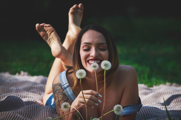 Foto porträt einer lächelnden jungen frau, die auf dem feld sitzt