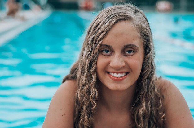 Foto porträt einer lächelnden jungen frau, die im pool schwimmt