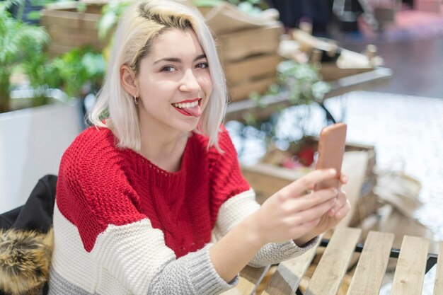 Foto porträt einer lächelnden jungen frau, die im restaurant ein telefon benutzt