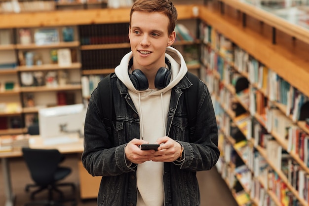 Foto porträt einer lächelnden jungen frau, die in der bibliothek steht