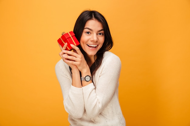 Porträt einer lächelnden jungen Frau, die kleine Geschenkbox hält