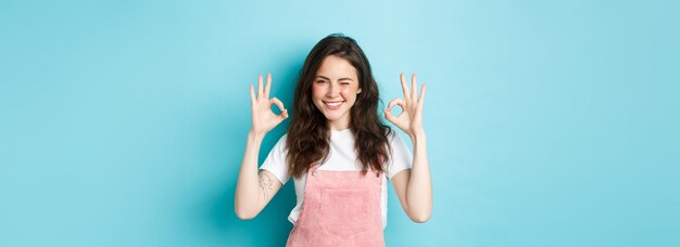 Foto porträt einer lächelnden jungen frau, die vor blauem hintergrund steht