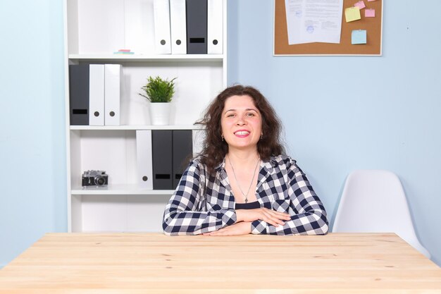 Foto porträt einer lächelnden jungen frau, die zu hause auf dem tisch sitzt