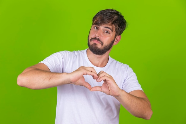 Porträt einer lächelnden jungen Frau hält die Hände auf der Brust in Herzform Zeichen drückt Sympathie aus Freundlicher, freundlicher netter Kerl mit weißem T-Shirt