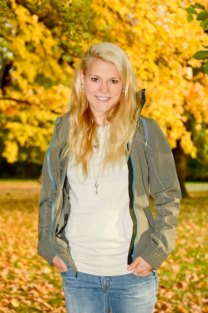 Foto porträt einer lächelnden jungen frau im park im herbst