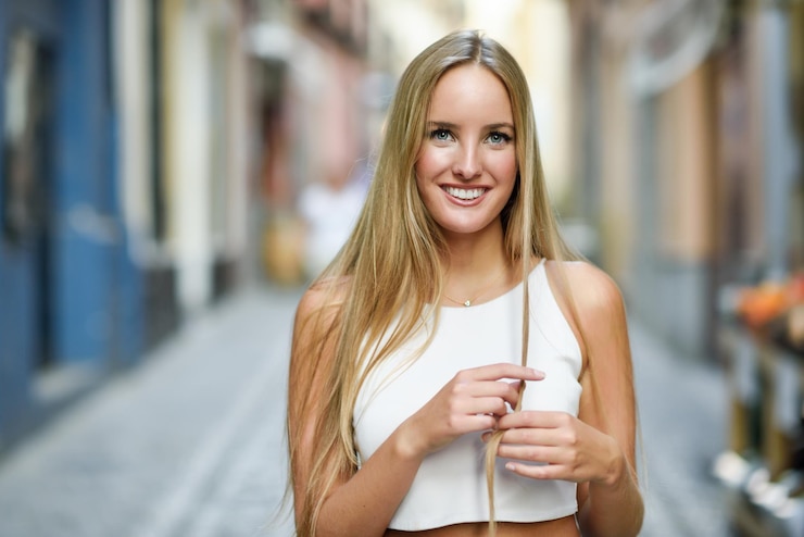 Foto porträt einer lächelnden jungen frau mit blonden haaren in der stadt