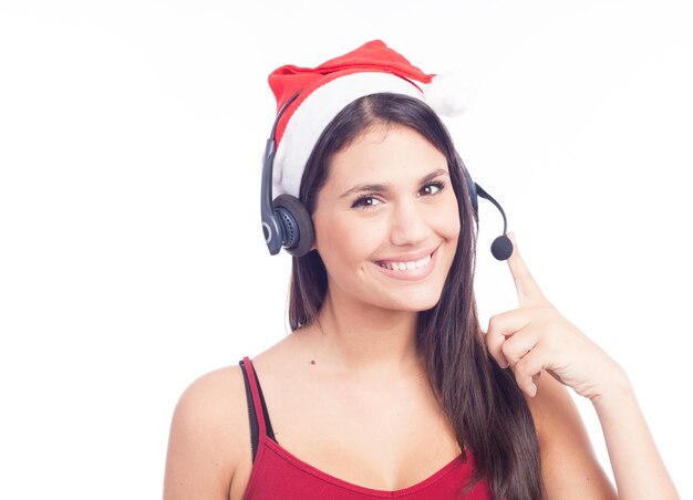 Porträt einer lächelnden jungen Frau mit Weihnachtsmannshut mit Headset auf weißem Hintergrund