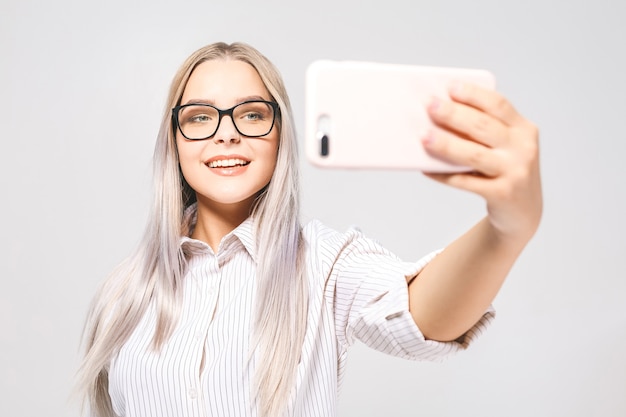 Porträt einer lächelnden niedlichen Frau in den Gläsern, die Selfie-Foto auf Smartphone machen