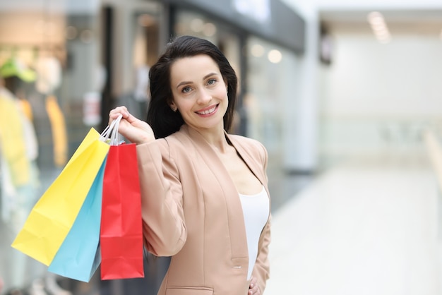 Porträt einer lächelnden, stilvollen Frau mit Einkaufstüten im Einkaufszentrum