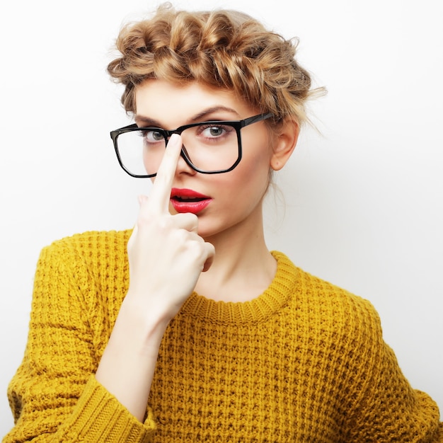 Porträt einer lässigen Frau mit Brille, die isoliert auf weißem Hintergrund in die Kamera schaut