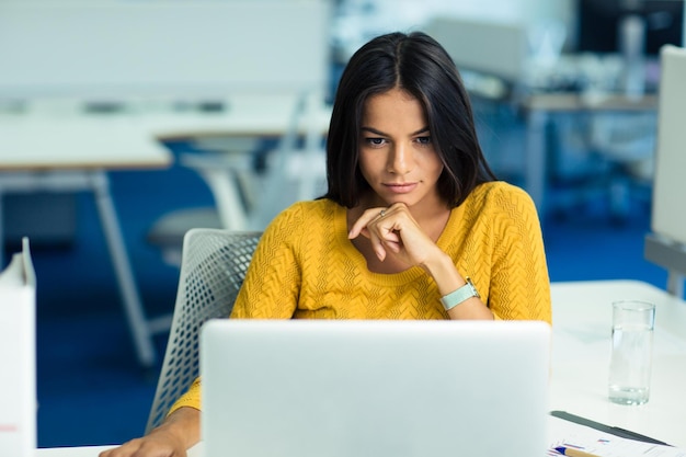 Porträt einer lässigen jungen Geschäftsfrau im Pullover mit Laptop-Computer im Büro