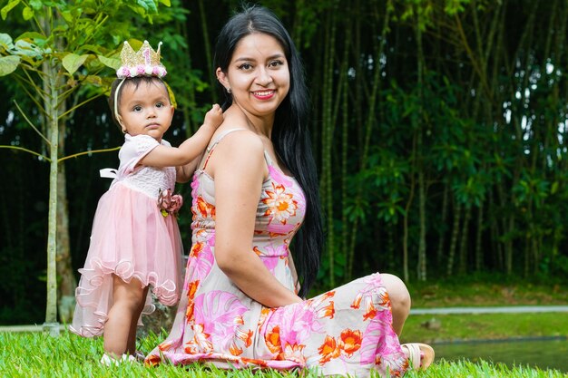 Porträt einer Latina-Mutter, die mit ihrem schönen brünetten Baby auf Gras sitzt