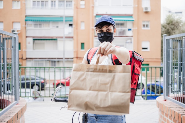 Porträt einer Lieferperson mit Maske, die ein Paket überreicht