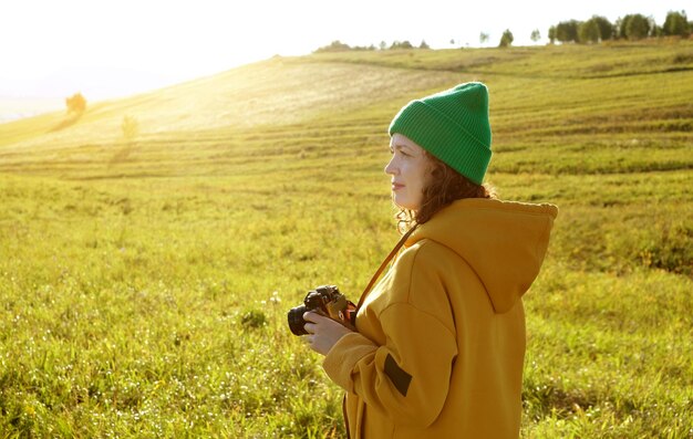 Porträt einer lockigen Fotografin im Freien. Frauen gehen und fotografieren mit ihrer Kamera