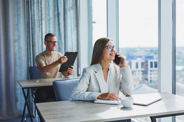 Porträt einer Managerin in formeller Kleidung, die Büroarbeit erledigt und am Telefon spricht, eine erfolgreiche europäische Chefin mit optischer Brille zur Sehkorrektur, die an ihrem Schreibtisch posiert