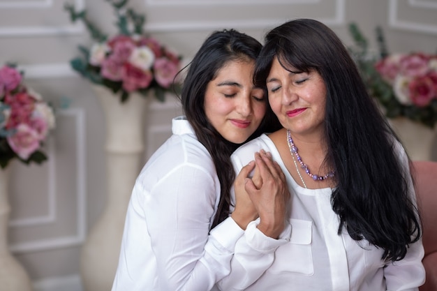 Porträt einer mexikanischen Mutter und Tochter, die sich am Muttertag umarmen