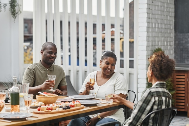 Porträt einer modernen afroamerikanischen Familie, die gemeinsam im Freien Getränke beim Abendessen genießt