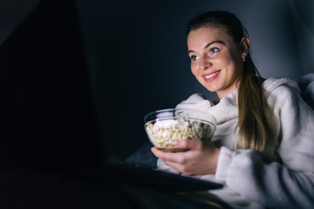 Porträt einer modernen jungen Frau, die Filme online über einen Laptop ansieht