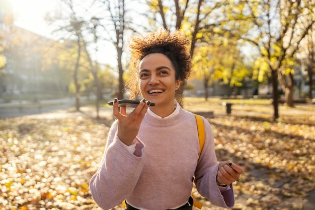 Porträt einer modischen jungen Frau, die auf der Straße eine Sprachnachricht im Telefon hinterlässt