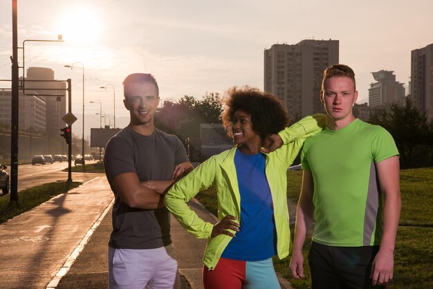 Porträt einer multiethnischen Gruppe junger Menschen am schönen Sommerabend beim Joggen, wenn die Sonne über der Stadt untergeht