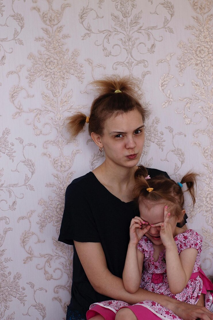 Foto porträt einer mutter, die ein gesicht macht, während sie mit ihrer weinenden tochter an der wand sitzt