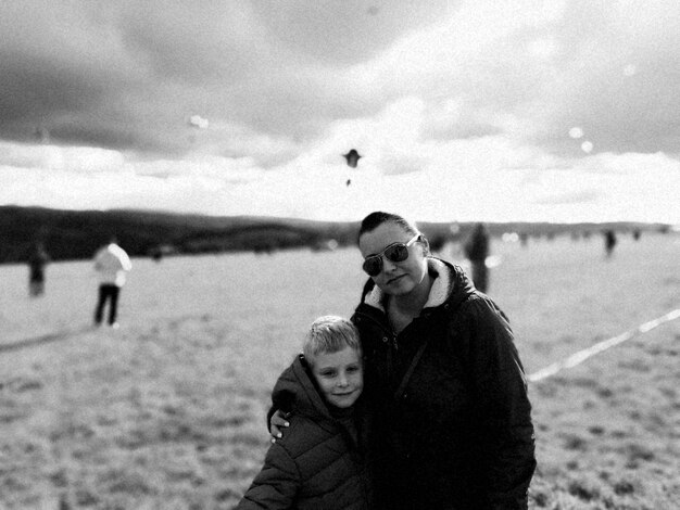 Porträt einer Mutter, die mit dem Arm um ihren Sohn am Strand steht