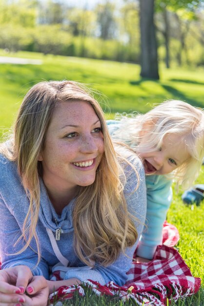 Foto porträt einer mutter mit einem baby, das auf dem gras sitzt