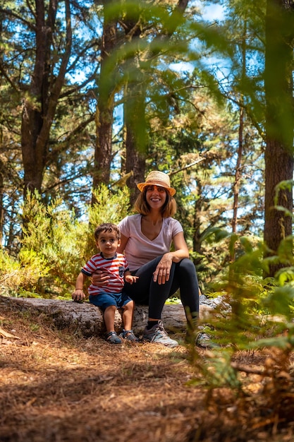Porträt einer Mutter mit ihrem Sohn, der auf einem Baum in der Natur neben Pinien sitzt Madeira Portugal