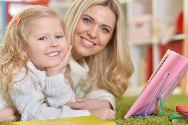 Foto porträt einer mutter mit kleiner tochter, die ein buch liest